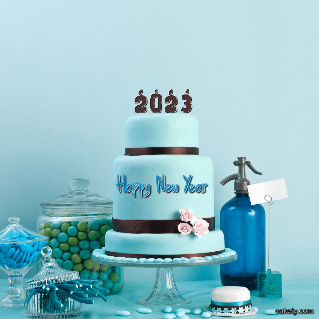 Una tarta de varios pisos con velas que indican 2023 en el piso superior. En colores azules, también se ve un sifón decorativo en los mismos colores y muchas golosinas y regalices, todo en tonos azules