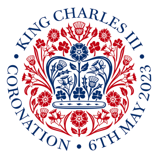 Emblema de la coronación en el que se ve en colores azul, una corona hecha de flores, rodeada de una estela de flores rojas y en redondo el texto siguiente KING CHARLES III · CORONATION 3 6TH MAY 2023